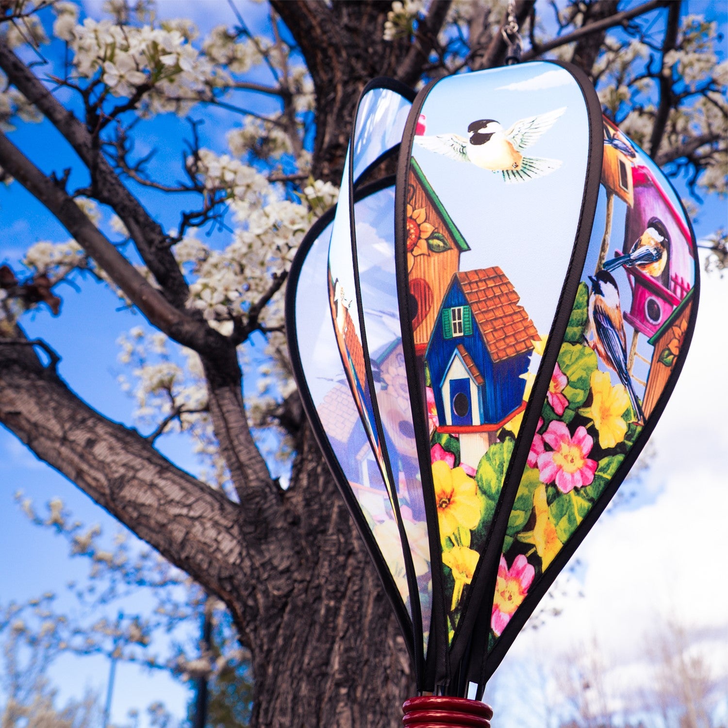 Chickadee Birdhouse Hot Air Balloon spinning in the breeze, showcasing vibrant chickadee graphics and a colorful curlie tail adorned from a wooden basket.