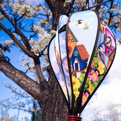 Chickadee Birdhouse Hot Air Balloon spinning in the breeze, showcasing vibrant chickadee graphics and a colorful curlie tail adorned from a wooden basket.