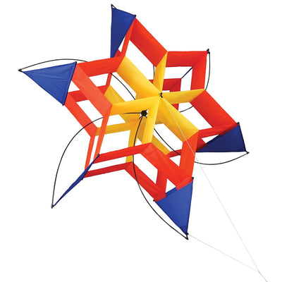 Circus Cosmic Hex Kite in bright colors soaring through a blue sky with clouds, showcasing its unique hexagonal design.
