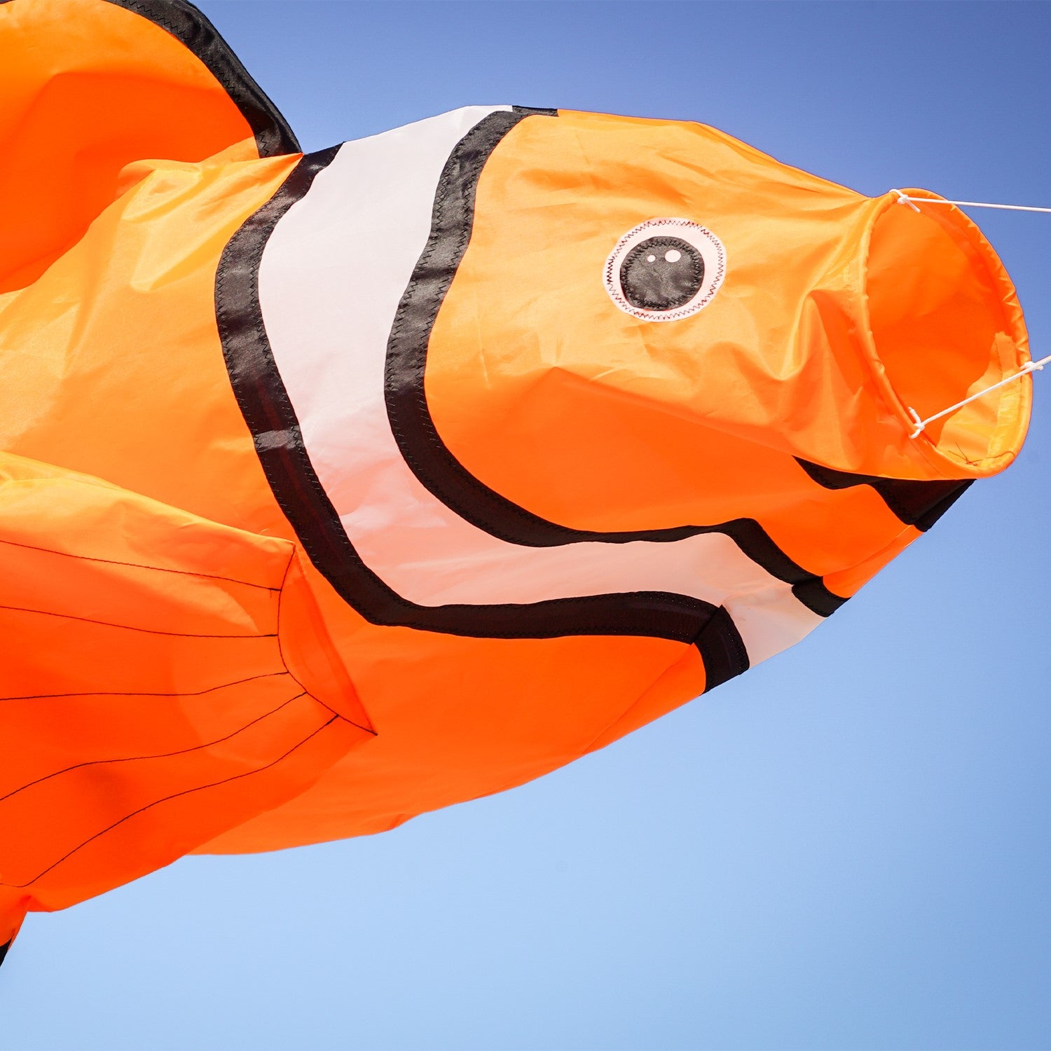 Clownfish Big Breeze WindsockTM, a vibrant 3D windsock with a detailed clownfish design, displayed in a garden setting swaying in the breeze.