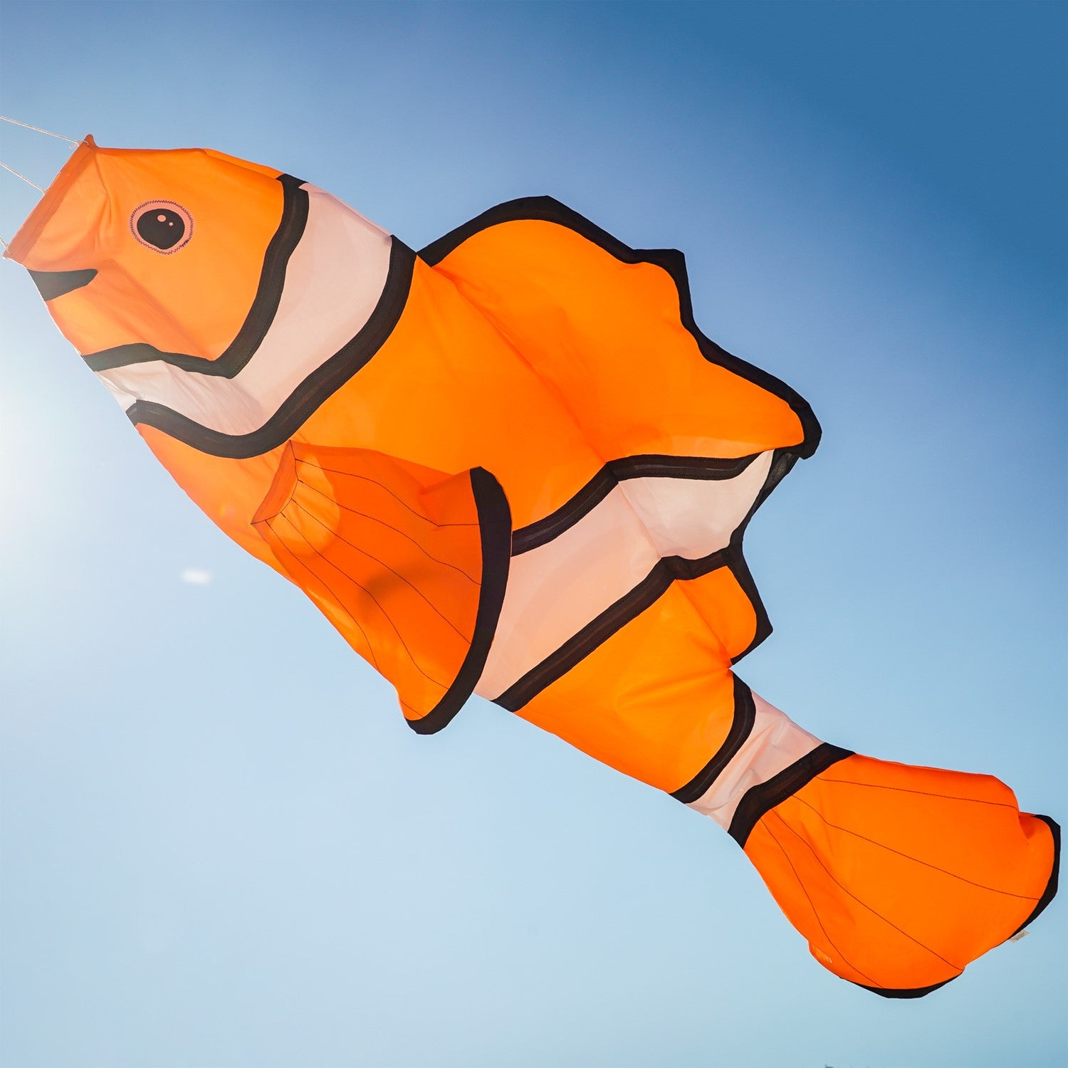Clownfish Big Breeze WindsockTM, a vibrant 3D windsock with a detailed clownfish design, displayed in a garden setting swaying in the breeze.