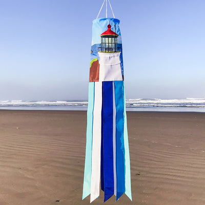 Coastal Lighthouse 40-inch windsock with vibrant lighthouse design and tails hanging elegantly from a garden in a coastal setting.