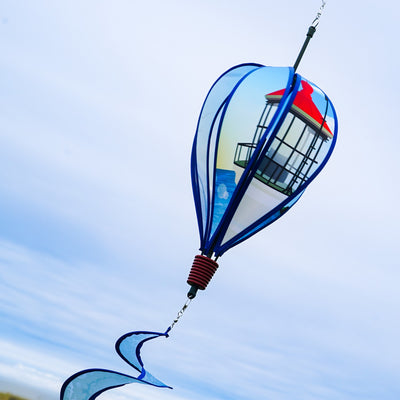 Coastal Lighthouse 6-Panel Hot Air Balloon spinner in vibrant colors with a lighthouse design hanging in a garden setting, spinning in the breeze.