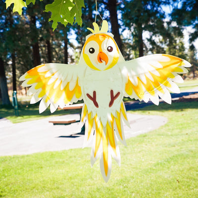 Colorful Cockatoo Windsock flapping gently in the breeze, showcasing its vibrant design with fully spread wings in an outdoor garden setting.