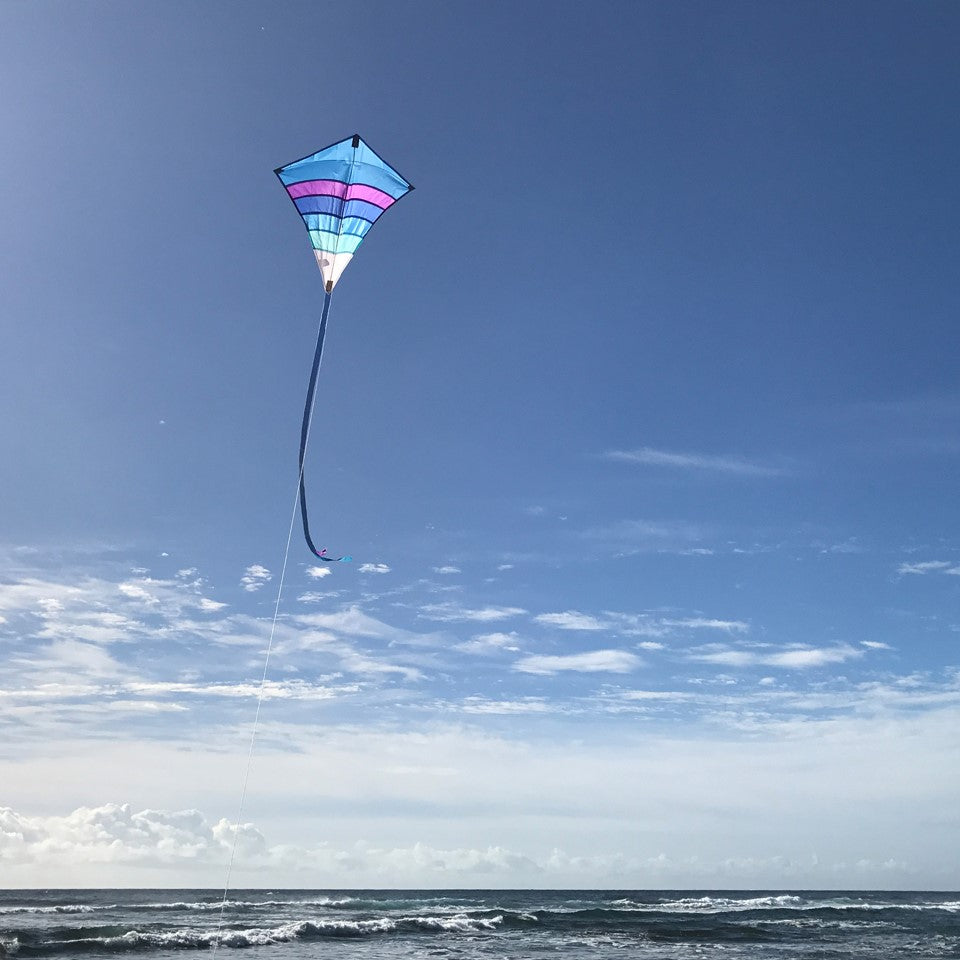 Cool Arch 27' Diamond Kite in vibrant rainbow colors flying high in a clear sky, ideal for beach and park activities.
