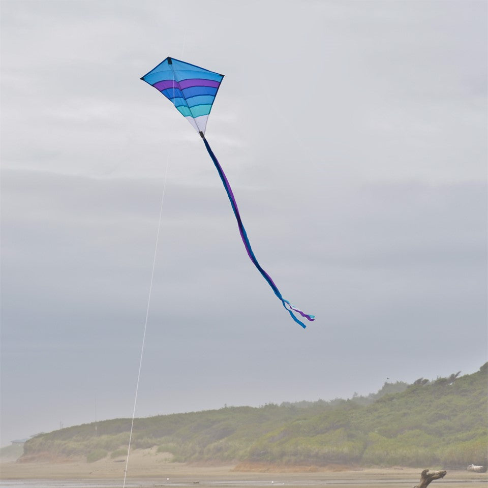 Cool Arch 27' Diamond Kite in vibrant rainbow colors flying high in a clear sky, ideal for beach and park activities.