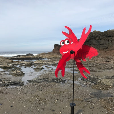 Crab Baby Whirligig garden decoration with vibrant crab design featuring spinning claws, displayed outdoors in a garden setting.