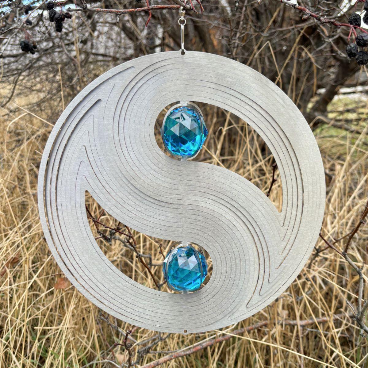 Crystal Yin Yang wind spinner displaying a gazing ball and colorful reflections, crafted from weather-resistant stainless steel for outdoor use.