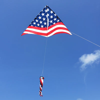 A 6.5 ft. Delta Kite - Old Glory Pack flying high in a clear blue sky, showcasing its vibrant colors and stable design.