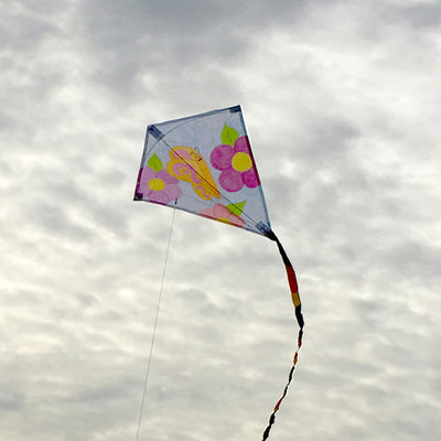 A Diamond Coloring Kite features a classic diamond shape, white weather-resistant fabric for coloring, and 78-inch rainbow tails for added flair.
