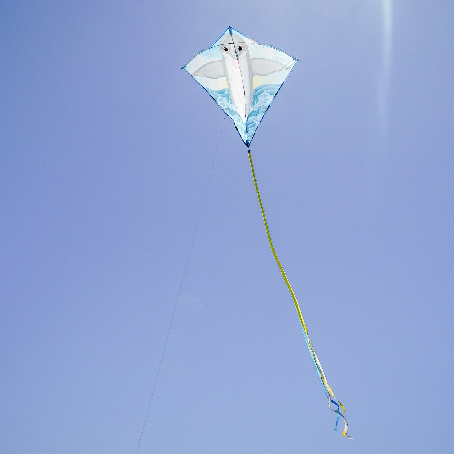 Dolphin 30 inch Diamond Kite soaring in the sky featuring a bright dolphin design, three color-coordinated tails stretching behind it.