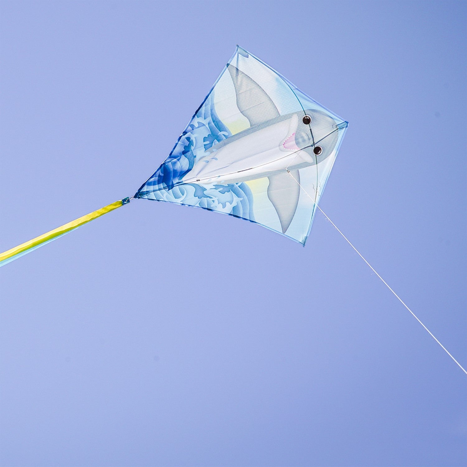Dolphin 30 inch Diamond Kite soaring in the sky featuring a bright dolphin design, three color-coordinated tails stretching behind it.