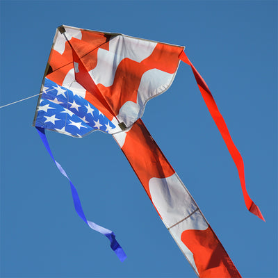 Easy Flyer Kite in patriotic colors soaring in the sky with a family flying it at a park, showcasing its vibrant design and large size.