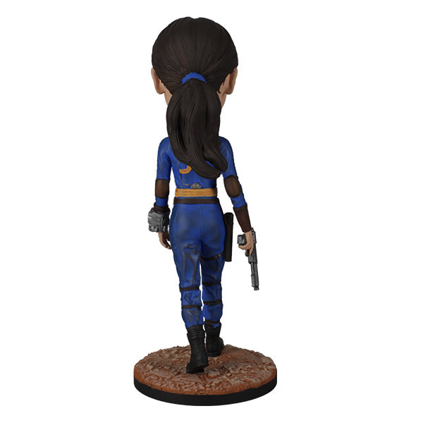 Fallout: Lucy MacLean Bobblehead standing proudly in a Vault 33 jumpsuit, ready for adventure with a rugged base reflecting the Wasteland.