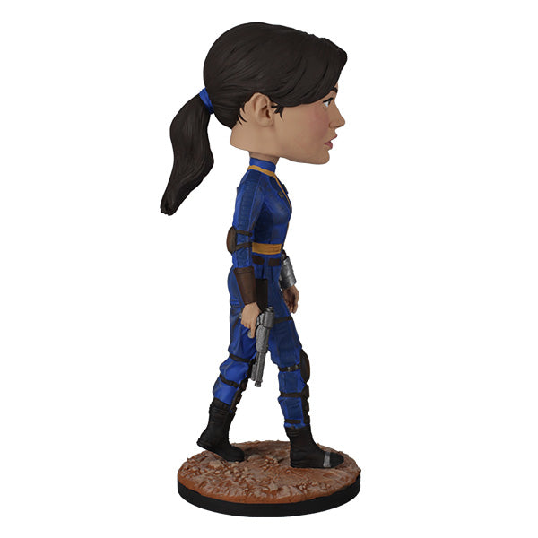 Fallout: Lucy MacLean Bobblehead standing proudly in a Vault 33 jumpsuit, ready for adventure with a rugged base reflecting the Wasteland.