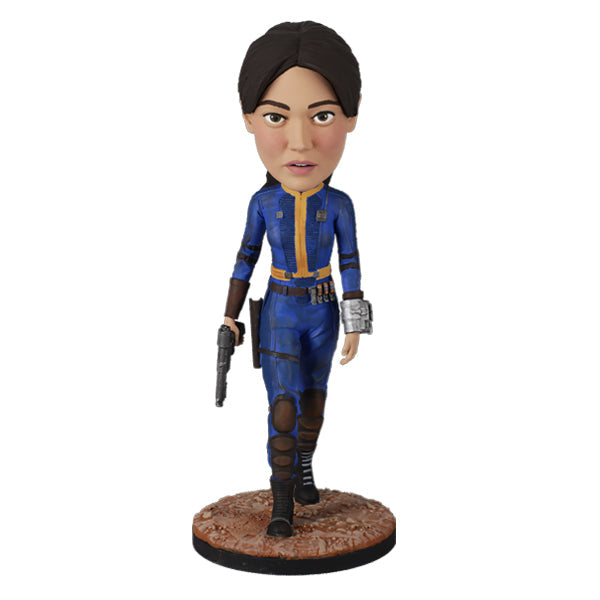 Fallout: Lucy MacLean Bobblehead standing proudly in a Vault 33 jumpsuit, ready for adventure with a rugged base reflecting the Wasteland.