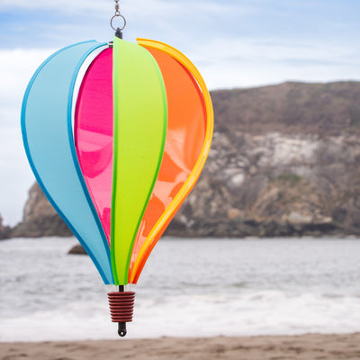 Colorful Fiesta 6-Panel Fabric Hot Air Balloon Spinner in a garden setting, highlighting its vibrant colors and balloon shape for outdoor decor.