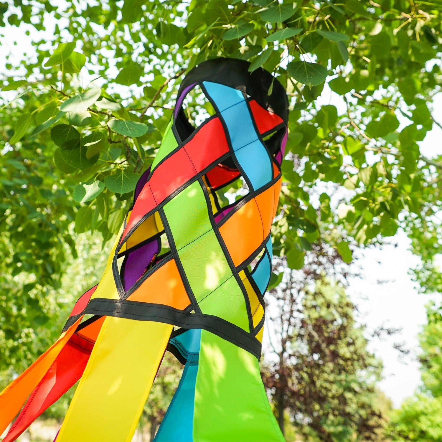 Fiesta Diagonal Weave 60\" Windsock with vibrant colors and black edging, fluttering in an outdoor setting against a bright blue sky.