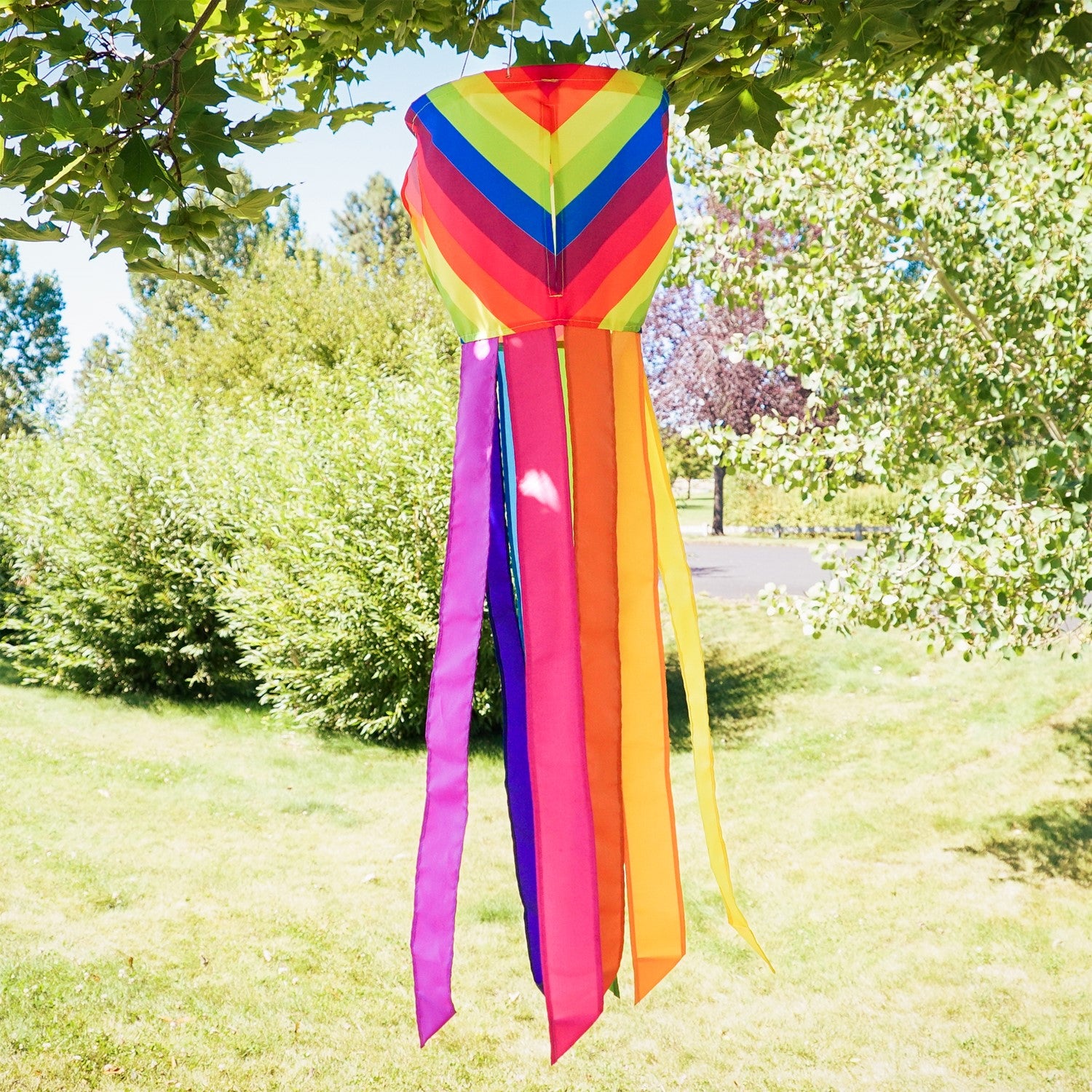 Colorful Fiesta Stripe Spinning Windsock featuring rainbow design with fluttering tails displayed outdoors, capturing motion in the breeze.