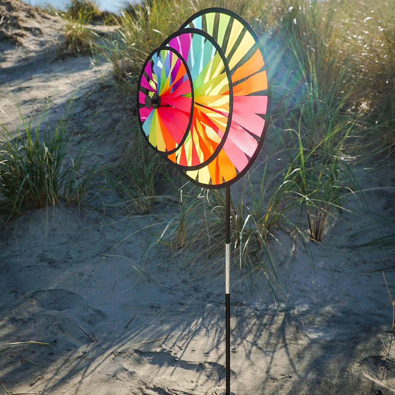 Fiesta Triple Wheel Spinner with three colorful wheels rotating in the breeze on a garden pole, showcasing a bright outdoor scene.