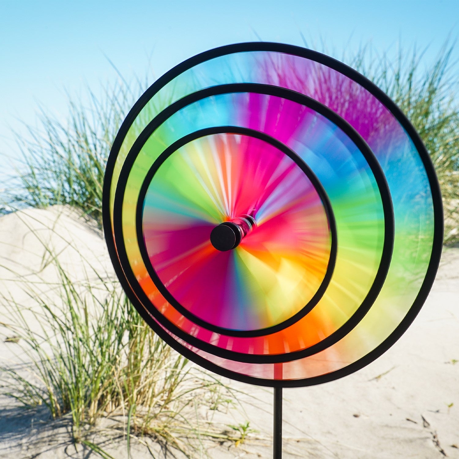 Fiesta Triple Wheel Spinner with three colorful wheels rotating in the breeze on a garden pole, showcasing a bright outdoor scene.