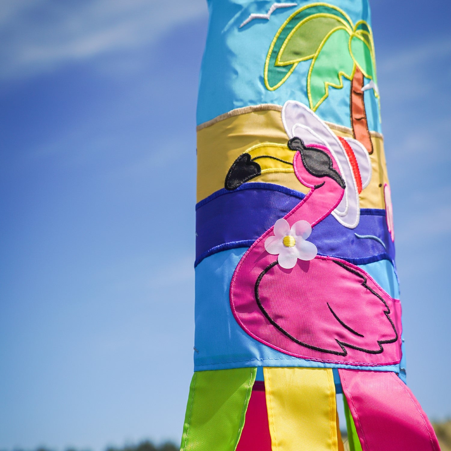 Flamingo 40" windsock with colorful design and embroidered details, fluttering in the breeze in a sunny garden setting.