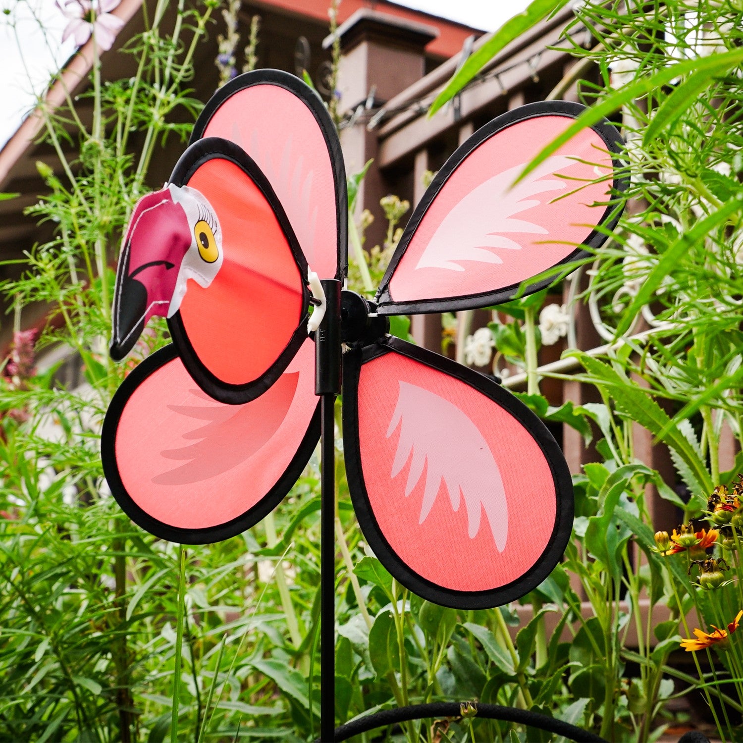 Colorful Flamingo Baby Spinner twirling on a fiberglass pole in a sunny garden, bringing joy and whimsical fun to the outdoor space.