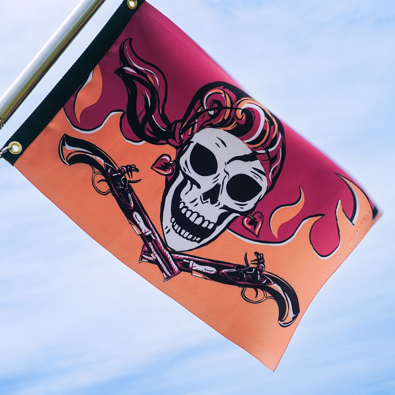 Flintlock Pirette Lustre 12x18 grommet flag displaying vibrant pirate-themed graphics, viewable from both sides, fluttering on an outdoor pole.