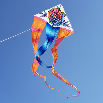 6.5 ft. Flo-Tail Delta Kite - Tattoo flying in clear blue skies, captivating viewers with its vibrant design and long flowing tails.