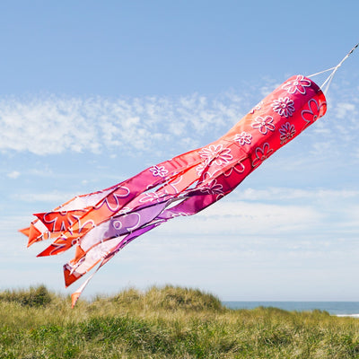 Flower Power 40-inch illusion windsock featuring vibrant flower designs and flowing tails, displayed hanging in a garden setting.