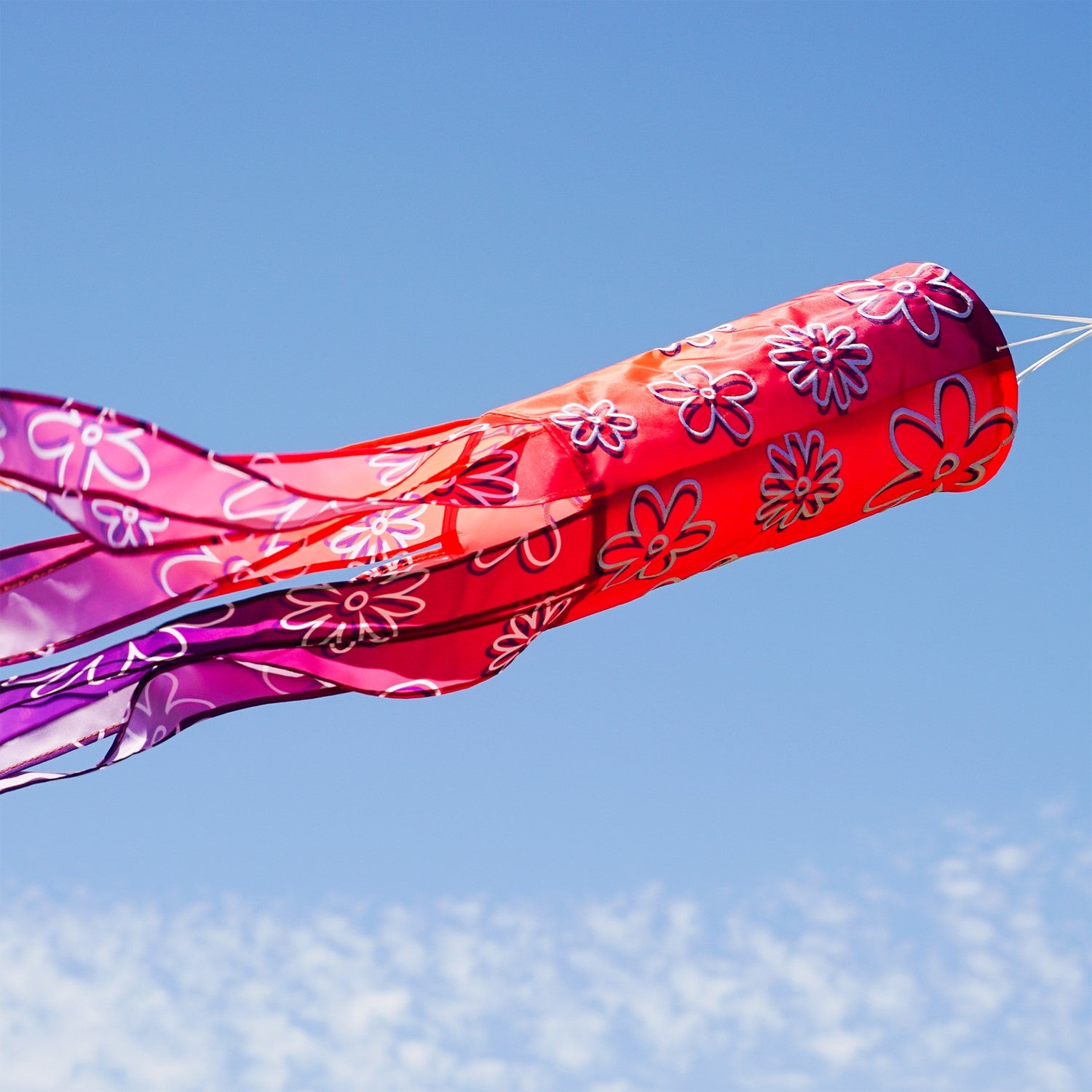 Flower Power 40-inch illusion windsock featuring vibrant flower designs and flowing tails, displayed hanging in a garden setting.