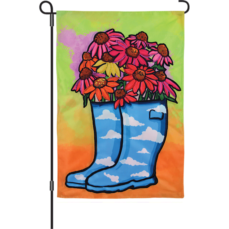 12 in. Flower Rain Boots garden flag featuring colorful rain boots and flowers displayed outdoors in a garden setting.