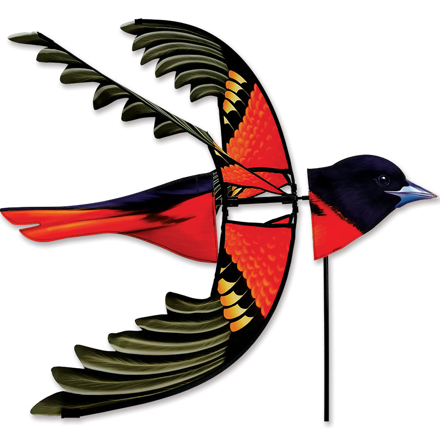 Flying Northern Oriole Spinner in bright colors, gracefully spinning in the wind among garden flowers, showcasing beautiful kinetic art.