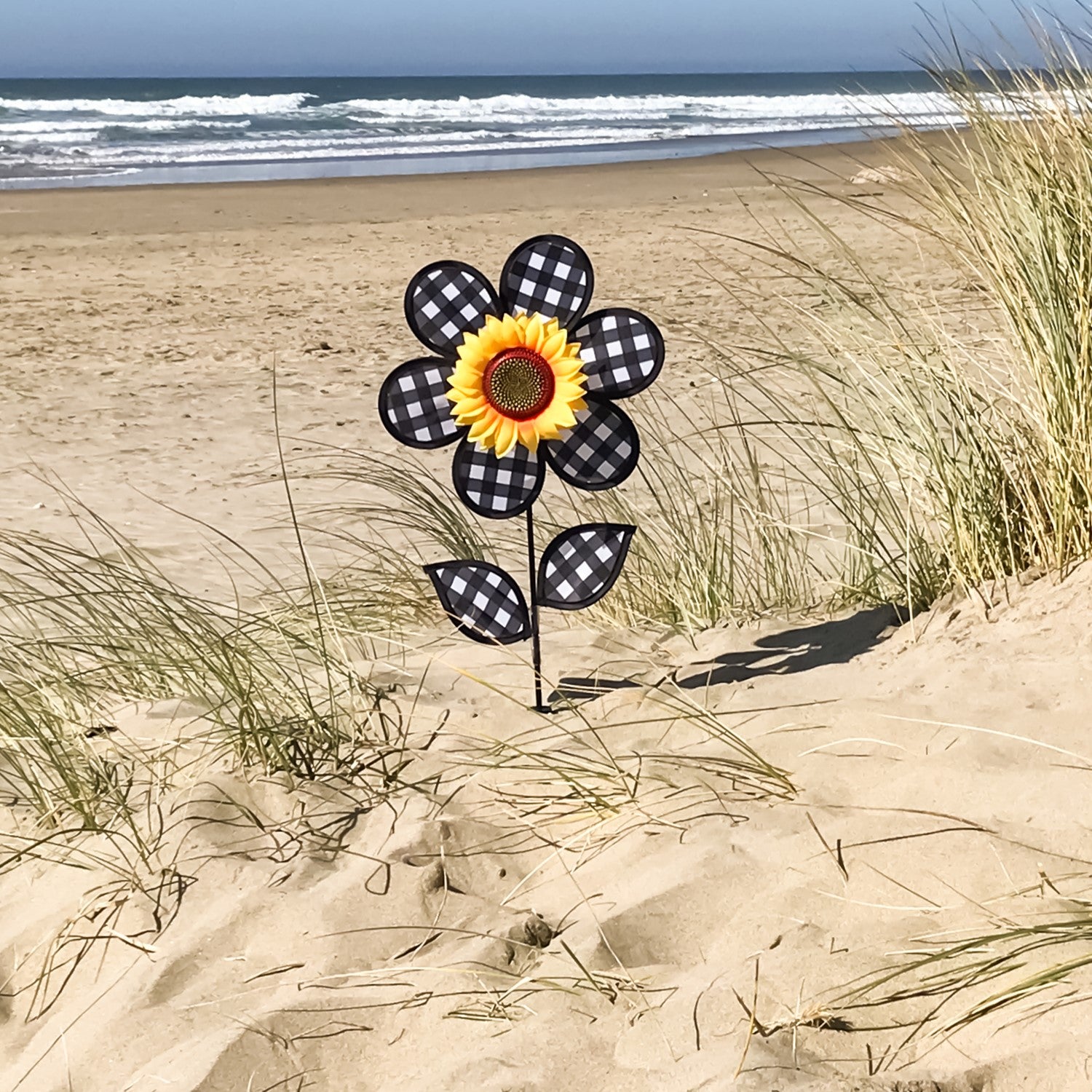 12-inch Gingham Sunflower Ground Spinner with black and white gingham petals and yellow center, spinning in a garden setting on a fiberglass pole.