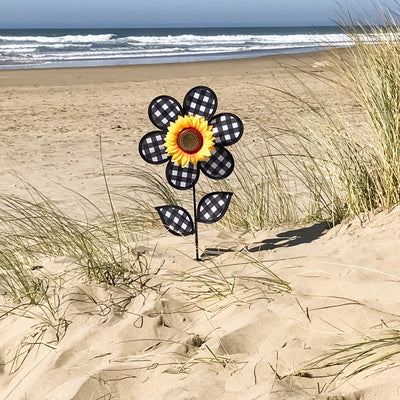 12-inch Gingham Sunflower Ground Spinner with black and white gingham petals and yellow center, spinning in a garden setting on a fiberglass pole.