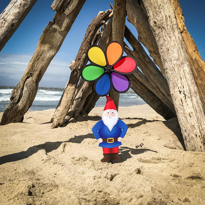 Gnome with 10-inch Rainbow Flower Spinner, featuring a whimsical design to brighten gardens, displayed outdoors with colorful motion in the breeze.