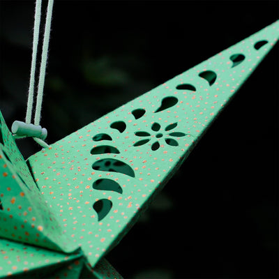Green Paper Star Lantern with intricate cutouts and gold accents hanging indoors, designed for soft, ambient lighting and decorative appeal.