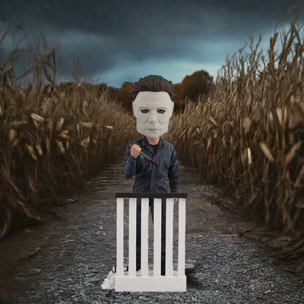 Halloween Michael Myers Bobblehead leaning over a stair railing, with a ghost sheet and glasses at his feet, capturing the essence of classic horror.