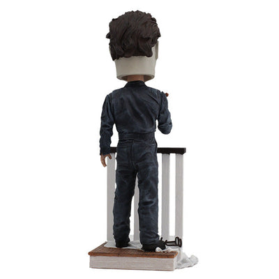Halloween Michael Myers Bobblehead leaning over a stair railing, with a ghost sheet and glasses at his feet, capturing the essence of classic horror.