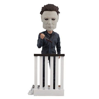Halloween Michael Myers Bobblehead leaning over a stair railing, with a ghost sheet and glasses at his feet, capturing the essence of classic horror.
