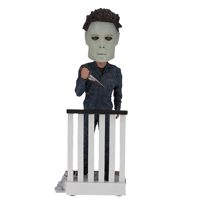 Halloween Michael Myers Glow in the Dark Mask Bobblehead leaning over a ghost-sheet prop with Bob's glasses, capturing slasher theme decor.