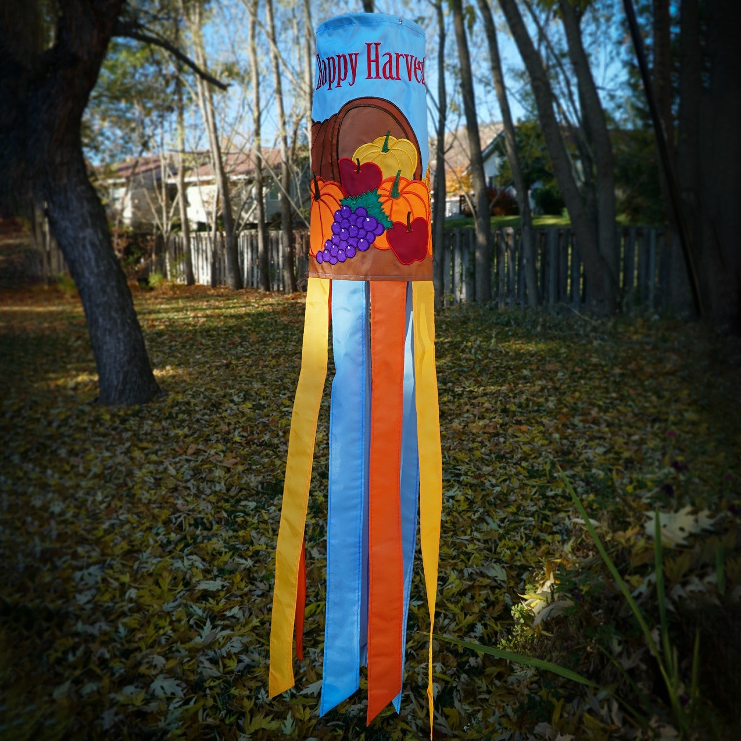Happy Harvest 40" Windsock featuring a cornucopia design with fruits and vegetables, fluttering gracefully in a garden setting during autumn.