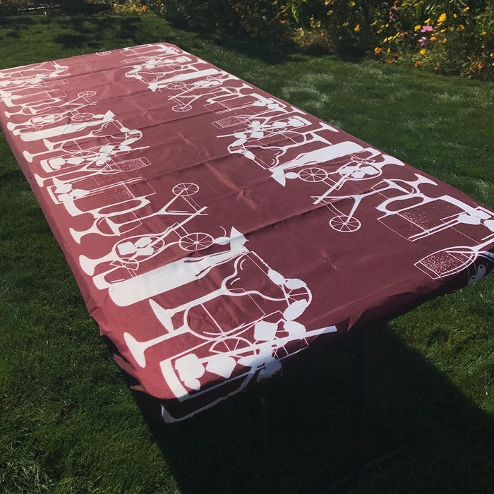 Happy Hour Drinks 8' Tablecloth featuring a vibrant design, secured to a picnic table in an outdoor setting, ideal for camping or events.
