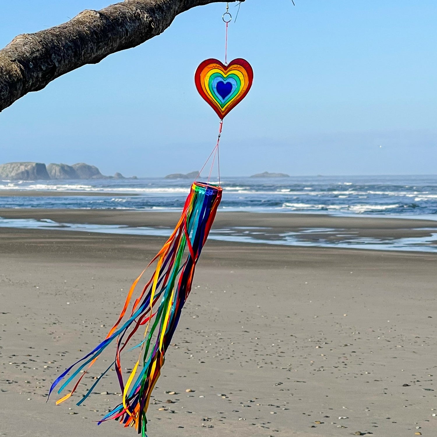 Heart & Ribbon Windsock featuring colorful rainbow satin ribbons cascading from a resin heart ornament, gently swaying in a garden setting.
