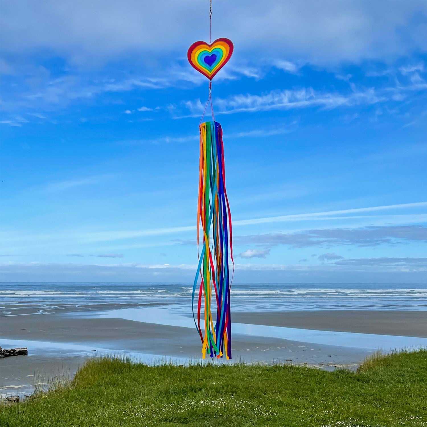 Heart & Ribbon Windsock featuring colorful rainbow satin ribbons cascading from a resin heart ornament, gently swaying in a garden setting.
