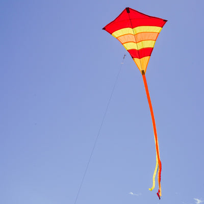 Hot Arch 27\" Diamond Kite with vibrant colors and 19-foot tails soaring in a clear blue sky, perfect for family outdoor activities.