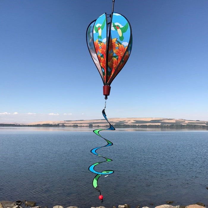 Hummingbird Lily Hot Air Balloon garden decor, showcasing vivid imagery of hummingbirds and lily flowers, spinning gently in the breeze.