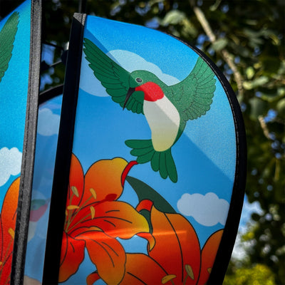 Hummingbird Lily Hot Air Balloon garden decor, showcasing vivid imagery of hummingbirds and lily flowers, spinning gently in the breeze.