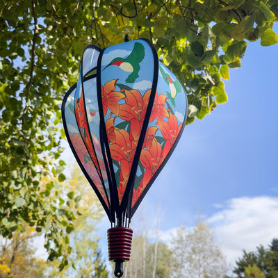Hummingbird Lily Hot Air Balloon garden decor, showcasing vivid imagery of hummingbirds and lily flowers, spinning gently in the breeze.