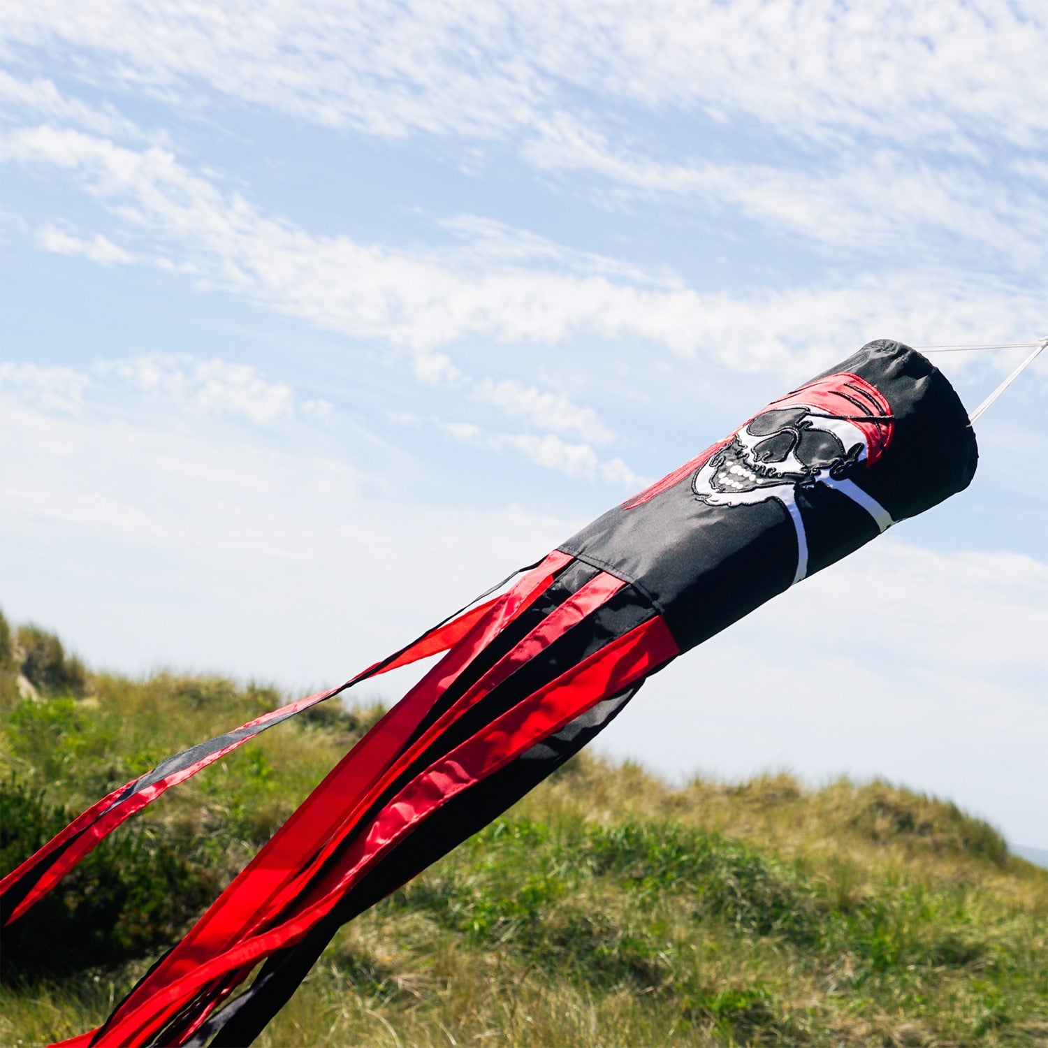 I'm a Jolly Roger 40" Windsock featuring a detailed pirate design with headscarf and gold earring, fluttering with vibrant tails in an outdoor setting.